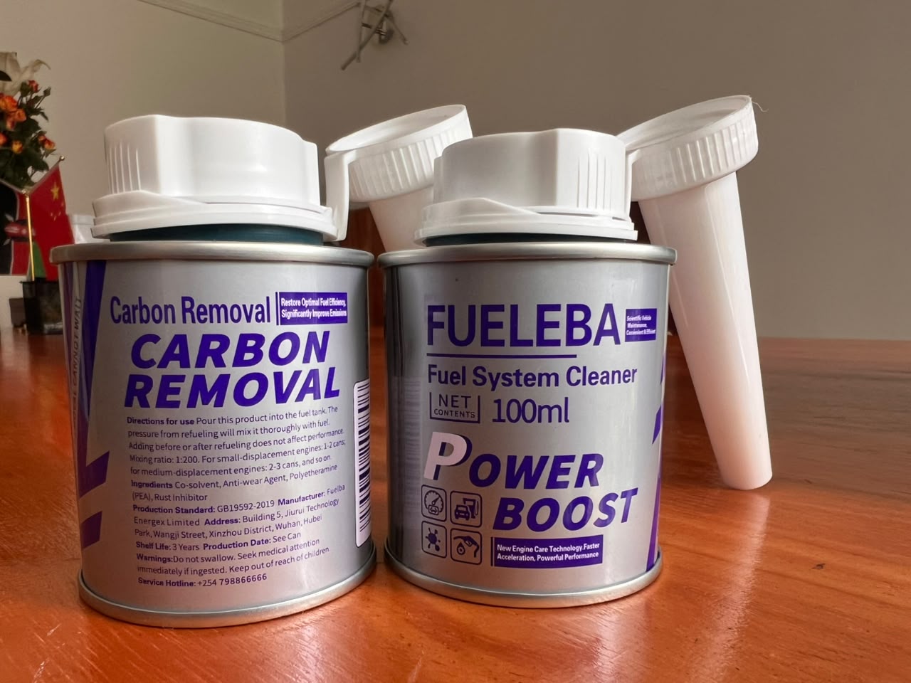Two open FUELEBA Power Boost cans with spouts removed, showing the Carbon Removal and Fuel System Cleaner labels